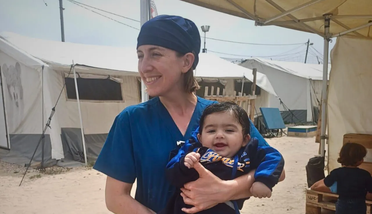 An ICRC physiotherapist holding a baby in their arms.