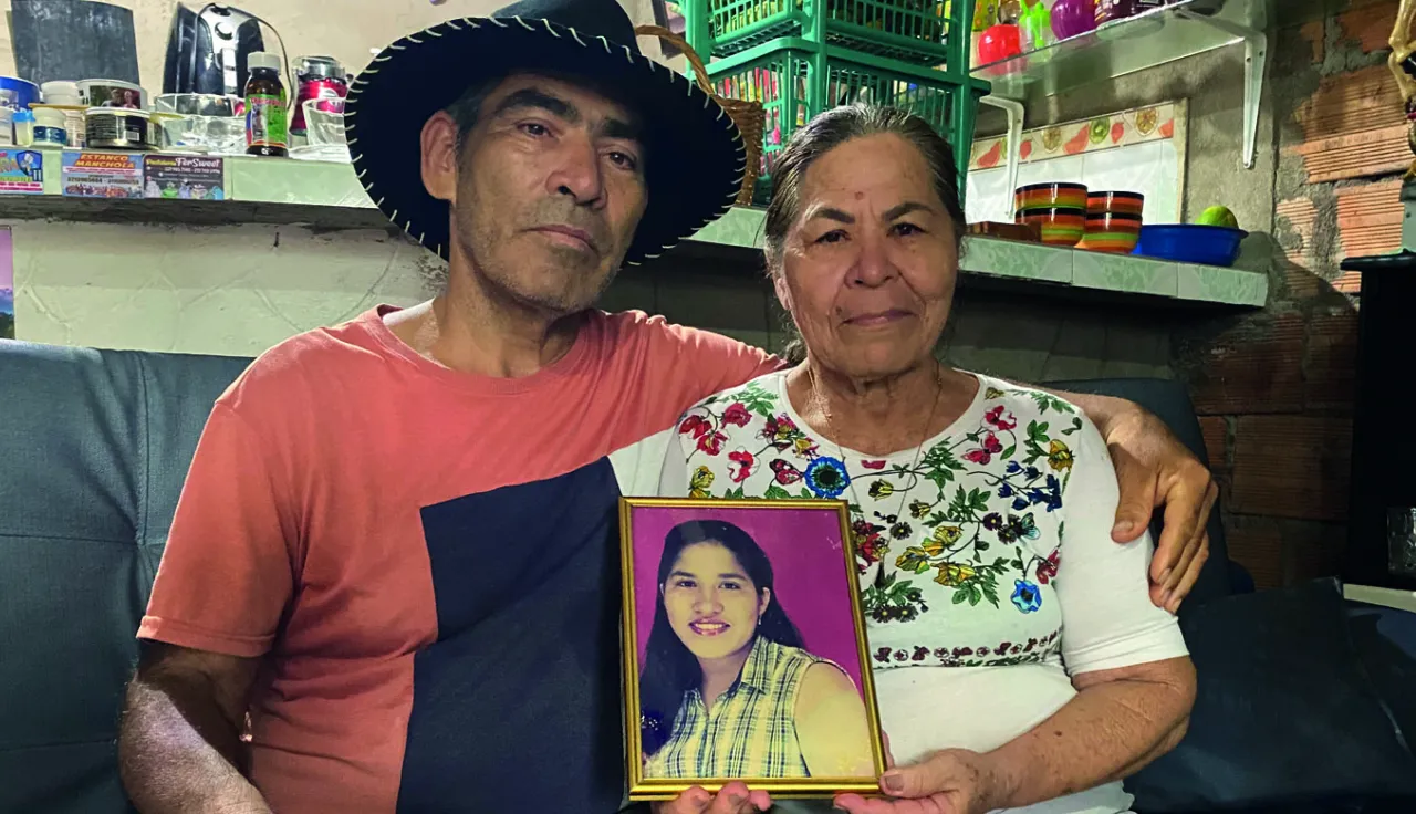 Dos personas sostienen el retrato de su hija desaparecida