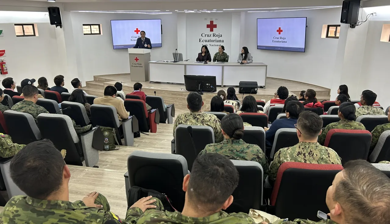 Un auditorio con miembros de las fuerzas armadas y un trabajador del CICR dando unas palabras.