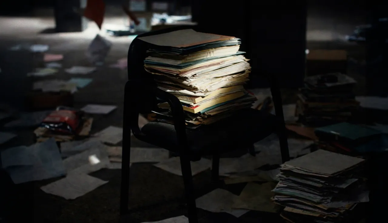 Folders on a chair, illuminated by a dim ray of light.