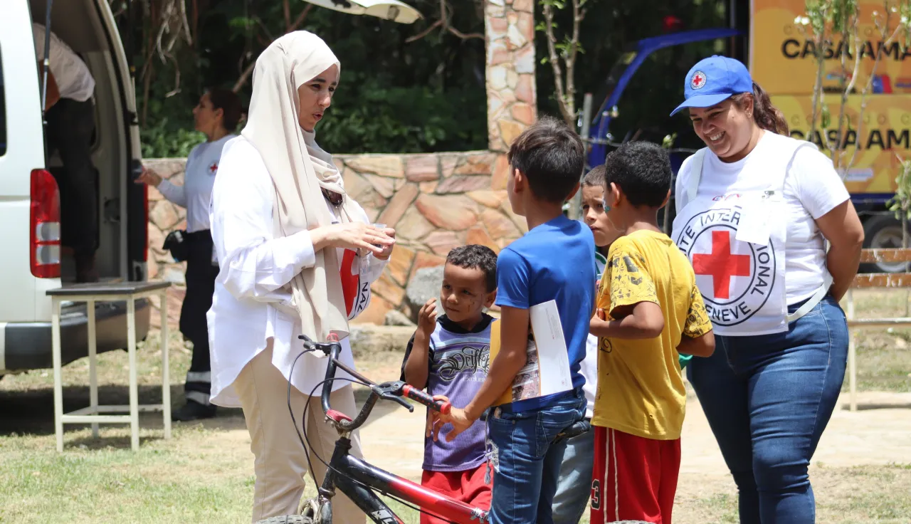 Durante una jornada de salud en el estado Aragua, dos trabajadoras del CICR están conversando con un grupo de niños