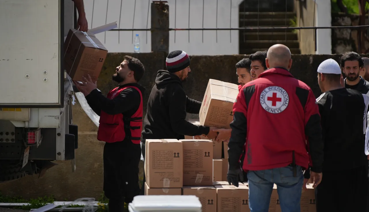 Staff from the International Committee of the Red Cross unloading a truck with aid parcels.