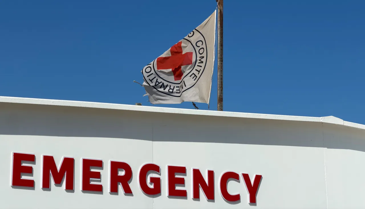 The ICRC flag flies above the emergency entrance of the Gaza Red Cross Field Hospital in Rafah, with signage in English and Arabic against a clear blue sky.