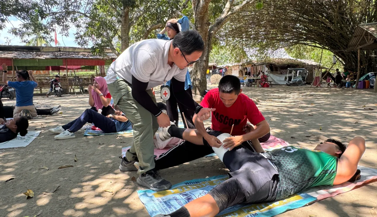 ICRC staff overlooks a participant pretending to be wounded while another applies first aid