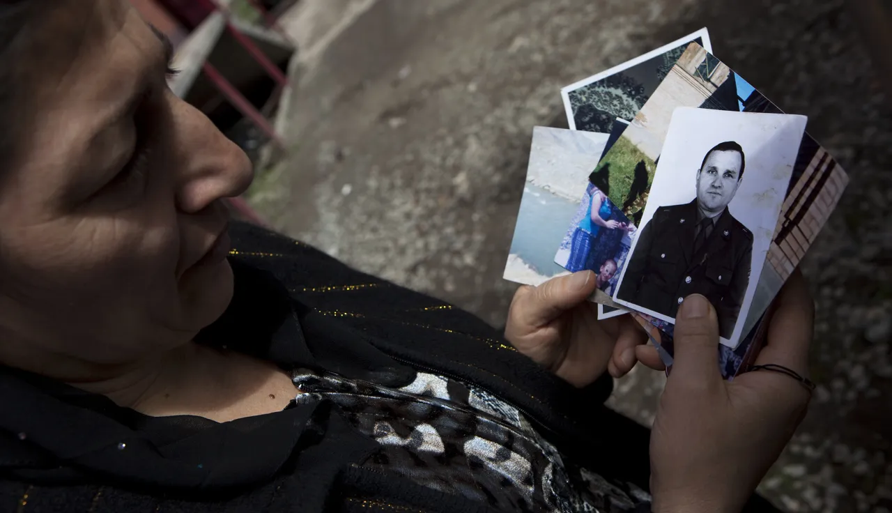 A woman is holding photos of her late husband