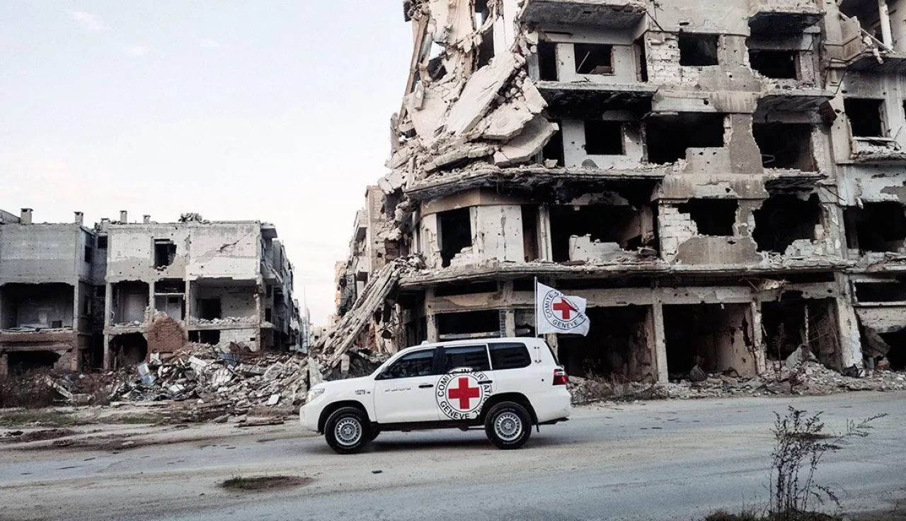 ICRC car next to buildings that have been destroyed by conflict 