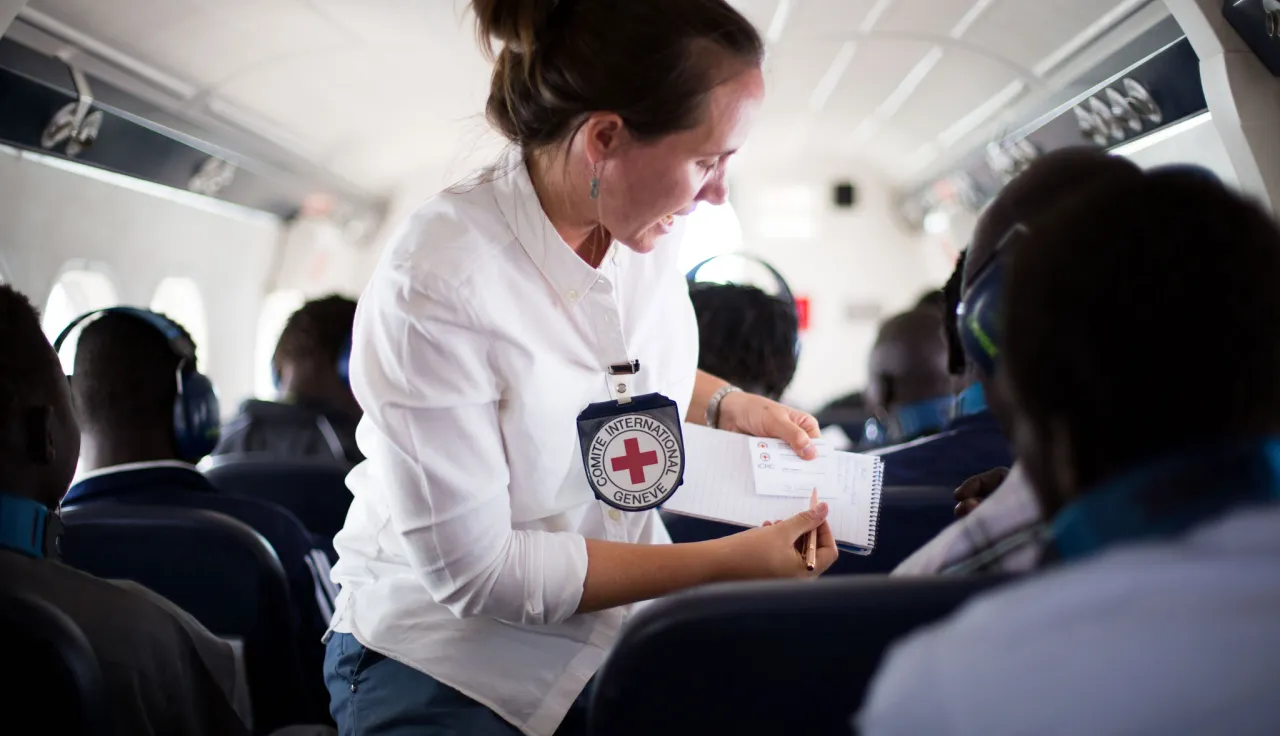 An ICRC staff member assists a released detainee during a humanitarian flight in South Sudan.