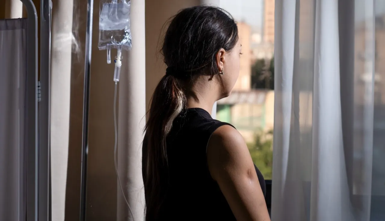 Tatev Aristakesyan's husband went missing following the escalation of conflict in 2020, in Armenia. It triggered severe health problems for Tatev and she slipped into a coma. ICRC Tatev Aristakesyan looks out of a window in a hospital and has her back to the camera.