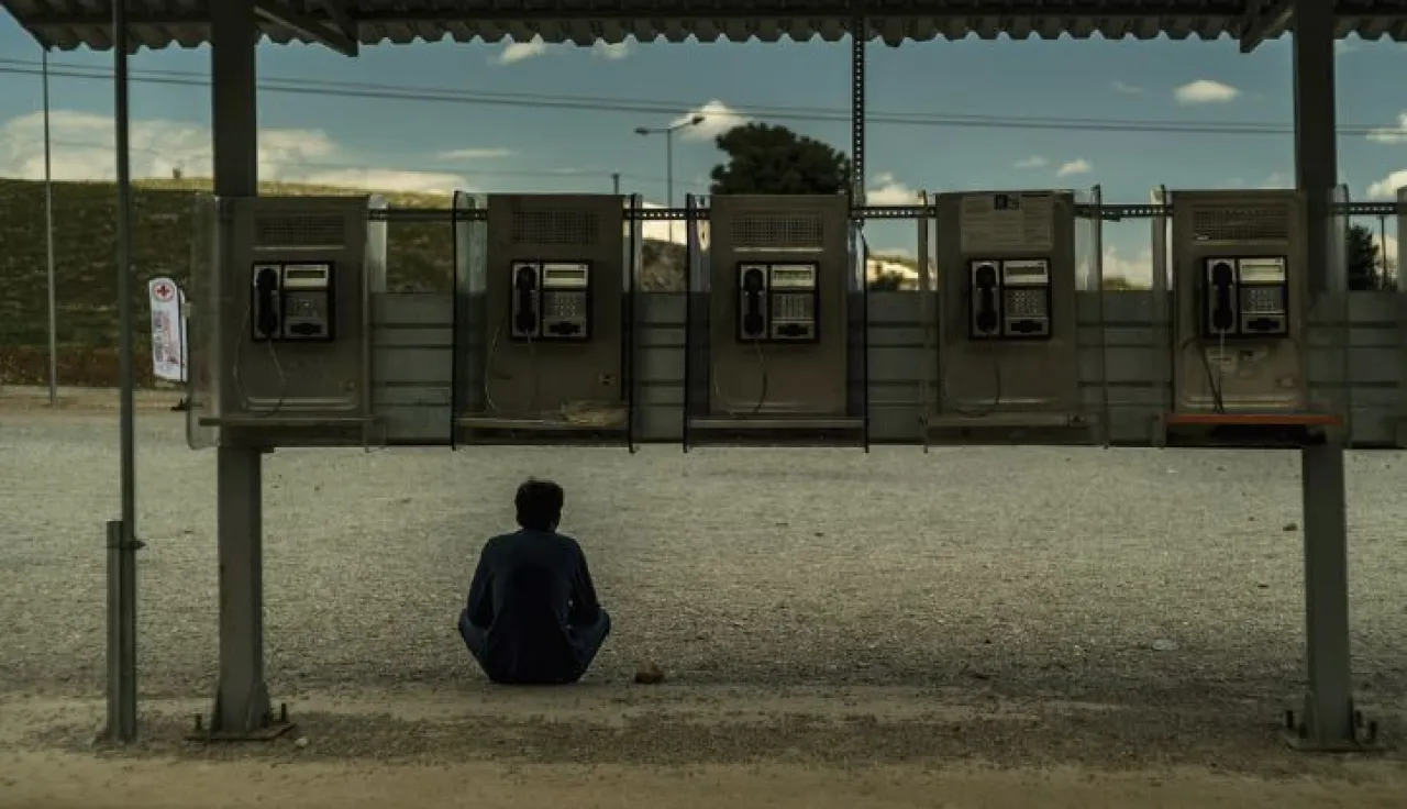 Man sitting in front of a row of public telephones