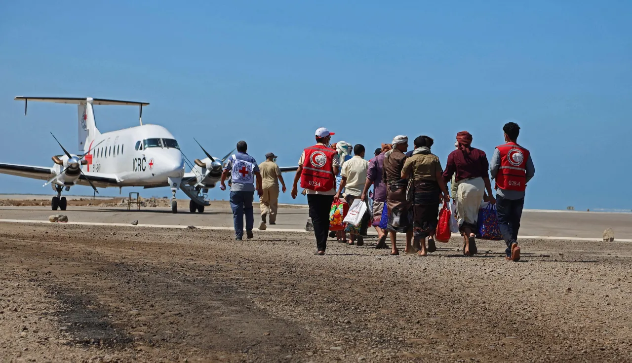 An ICRC staff escorts released detainees toward an ICRC plane at Mokha Airport, Yemen.