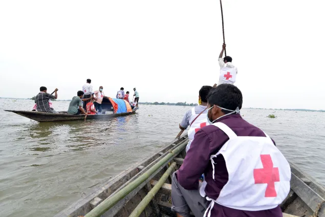 Volunteers of the Indian Red Cross Society travel in a boat to flood-affected districts in Assam, India, to distribute essential items.