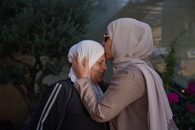 A woman kisses another woman on the forehead