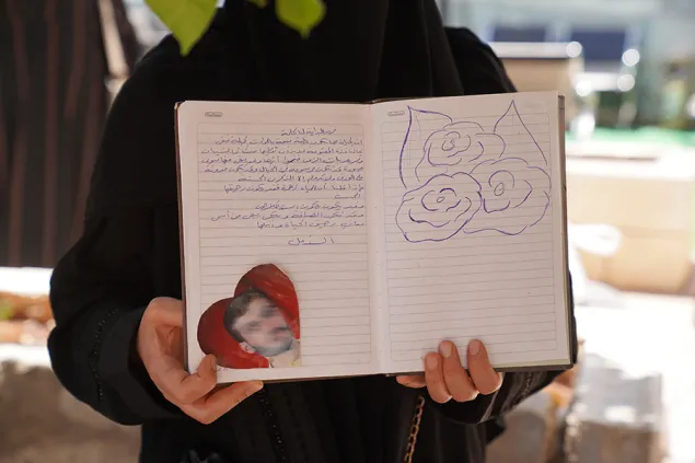 A woman holds a book with a picture of a missing relative in the shape of a heart
