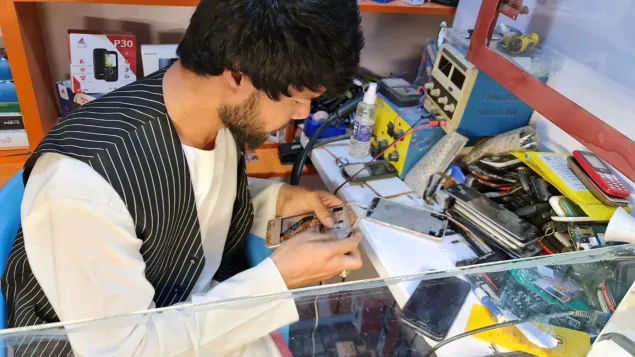 Baqir repairs a smartphone in his workshop in Mazar-i-Sharif