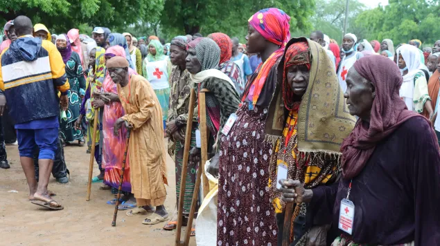 A large group of people standing in an area affected by floods