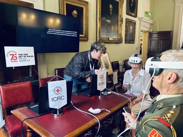 Two people wearing virtual reality headsets sat around a table