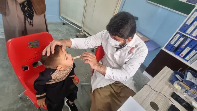 Little Khalid Ahmad is being medically examined by a health physician in an ARCS BHC in Kandahar