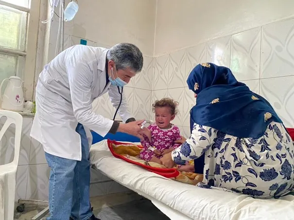 An Afghan Red Crescent Society (ARCS) doctor examines a patient at the Ghazi City Basic-Health-Care Centre