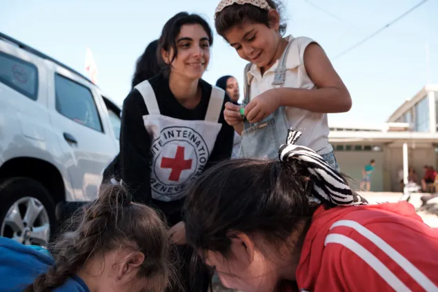 Batoul plays with an ICRC staff member and two other little girls