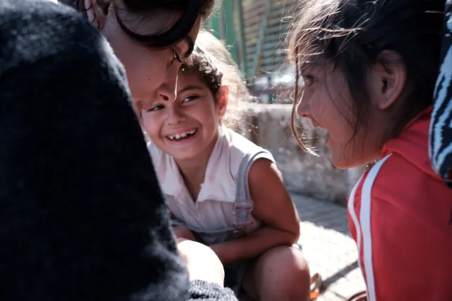 Lebanon IDP Maria and Batoul Maria in side profile smiling, with a smiling Batoul in the centre of the picture and the side profile of an ICRC delegate to the left