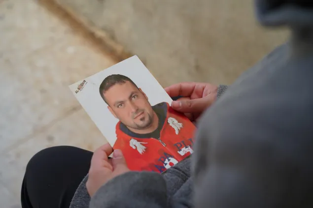 The daughter of family of missing person holding her father's picture
