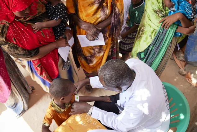 A child at the triage, getting his arm measurements taken.