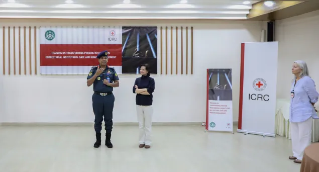 Two people presenting in training hall with ICRC banner in background