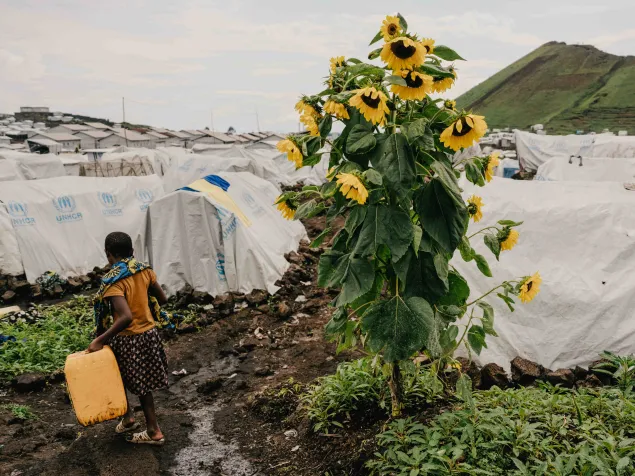 Una niña regresa de buscar agua de un punto de distribución en el campamento de desplazados de Lushagala.