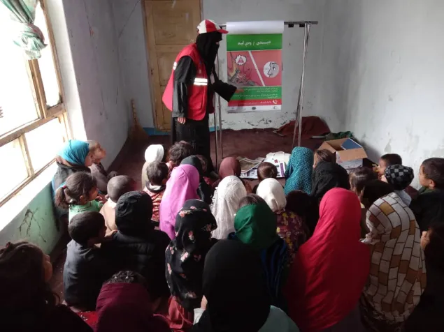 Children of a community with an ARCS RASB volunteer addressing the risks of explosive hazards