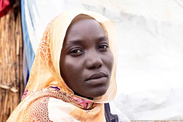 Someya, wearing a yellow headscarf, looks at the camera