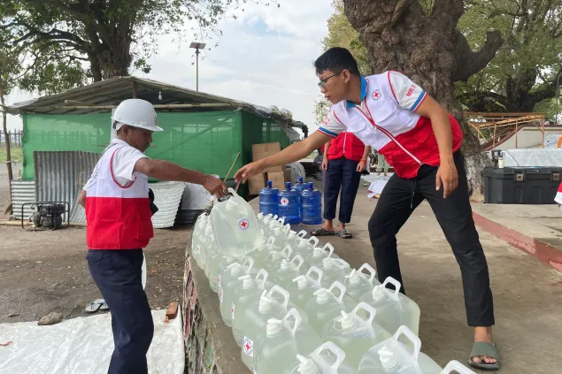 ICRC workers providing clean water containers in Myanmar