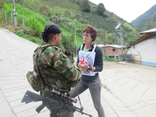 An ICRC staff talks with an armed soldier in the middle of the road. ICRC