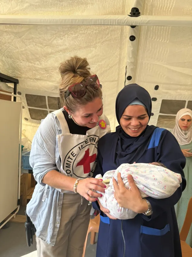 Baby Asia - born while stray bullets were around the field hospital in gaza - with midwife  Falasteen Qishta and ICRC staff member Sarah Davies.jpg