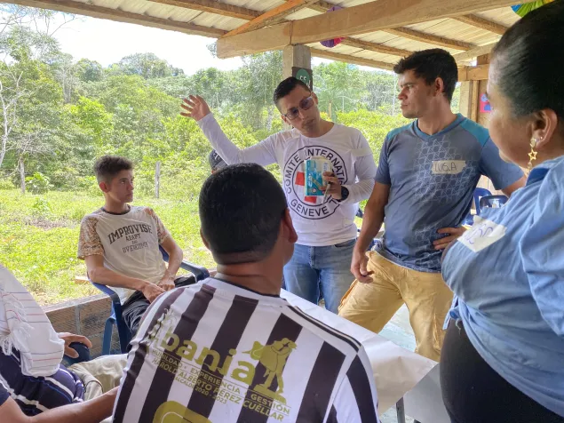 En una comunidad rural, un integrante del CICR se dirige a un grupo de personas reunidas, en un espacio de diálogo y encuentro comunitario.