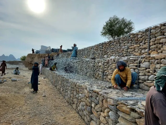 Community workers while positioning gabion baskets to construct a flood wall in Gulistan district of Farah Province.