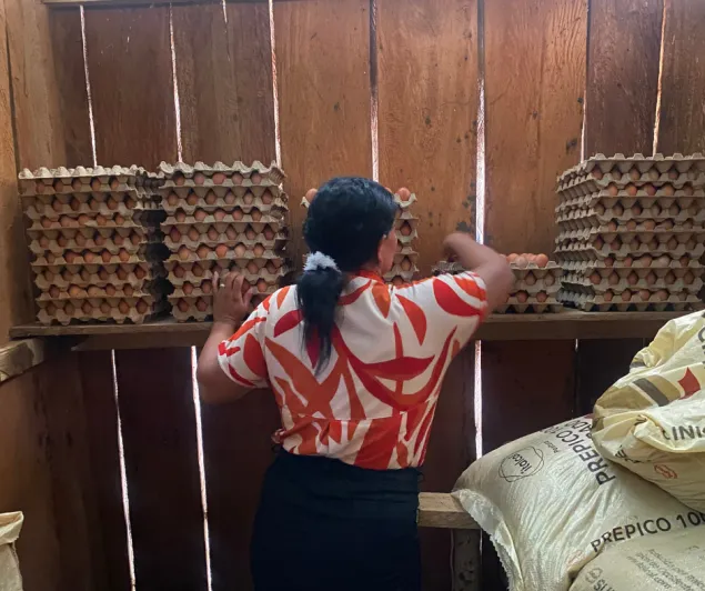 Una mujer, de espaldas, toma huevos en el interior de una bodega dedicada a su almacenamiento.