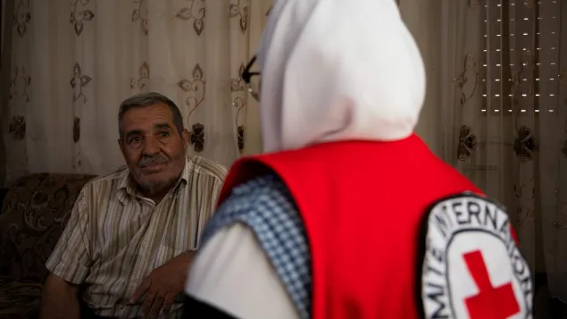 Ahmad sitting facing the camera facing a woman in an ICRC vest whose back is to the camera