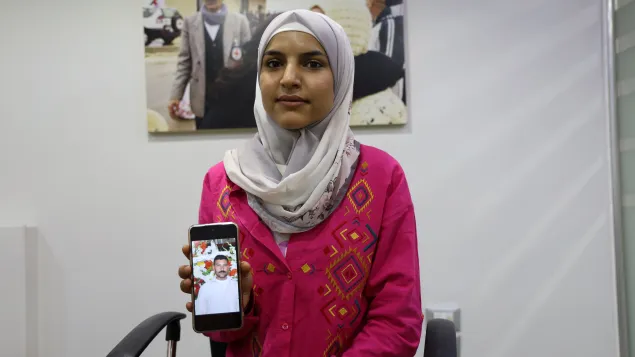 Lana Noamaan holds up a smart phone with a picture of her father