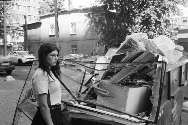 Viktoriia with broken window frames from her apartment, damaged in the strike.
