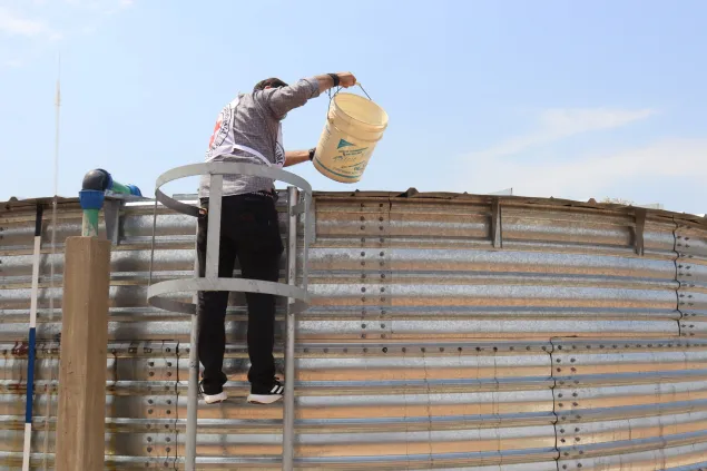 Un trabajador del CICR est[a sacando agua del tanque instalado en Magdaleno