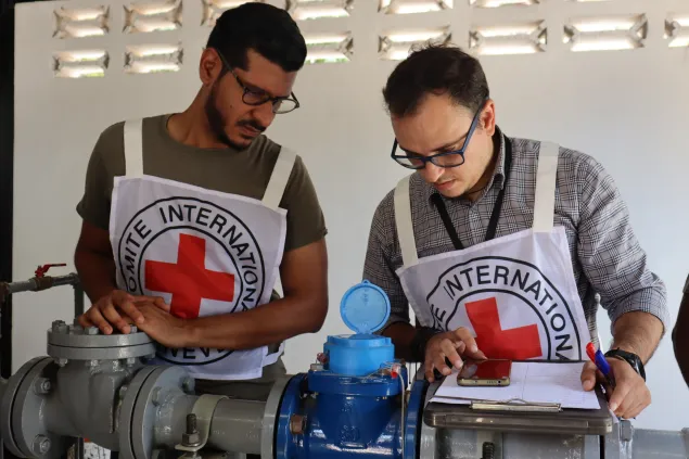Dos trabajadores del CICR están revisando las tuberias que están en la caseta de bombeo