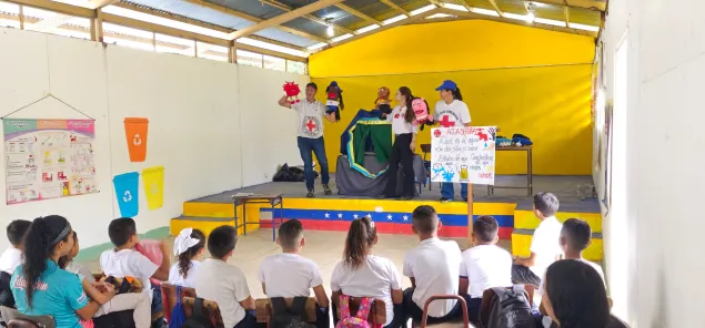 En un colegio de la comunidad, varios voluntarios de la Cruz Roja y un trabajador del CICR están haciendo una dramatización para los estudiantes