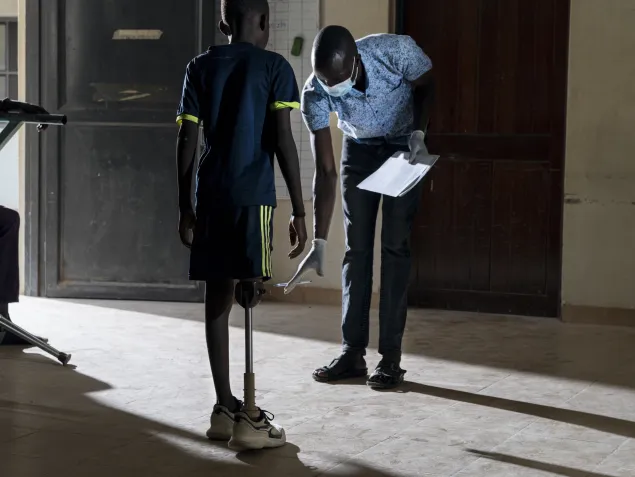 Physiotherapist  Apeleo Samson Emor helps 12-year-old Abdel Majid Juma learn to walk with his newly fabricated artificial limbs.