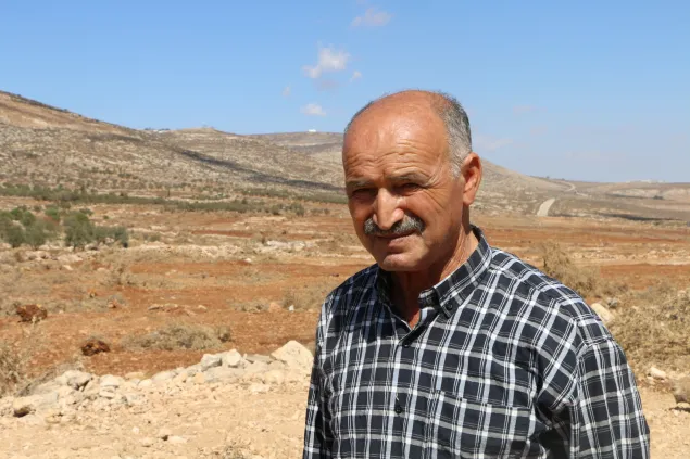 Abu Wahid standing in front of a plot of land where thousands of olive trees were uprooted.