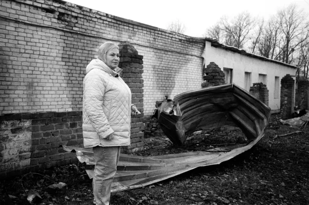 Tetiana Pasmor, Director of a water company in Chuhuiv, Kharkiv Oblast, stands beside wreckage caused by a strike across the road from her office. 