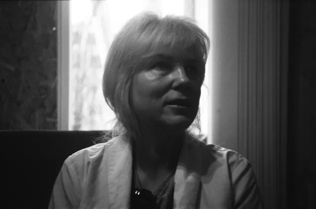 Nina Aleksandrova, director of a primary health centre in Petropavlivka, sitting in front of boarded up windows and with a damaged hospital visible in the background.