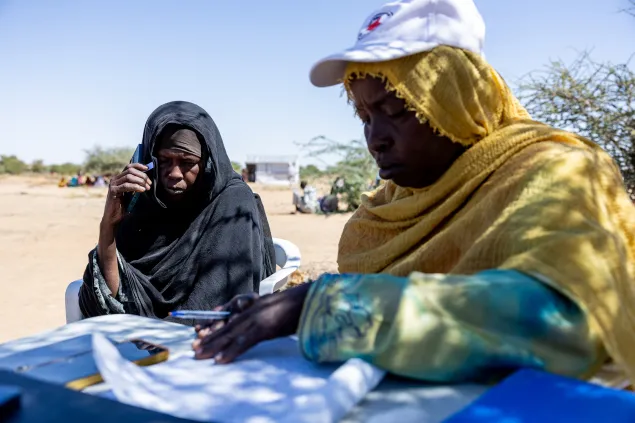 Awa Doug Azib, 55, calls her son on 22 November 2025, using the phone made available by the ICRC and the Red Cross of Chad at the entry point to Ouré Cassoni camp, Ennedi East (Chad), where she arrived the previous month.