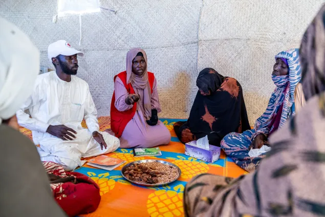 Hamed Tiara Youssouf and Nidal Abakar Abdelkerim, psychosocial workers with the Red Cross of Chad, speak with Sudanese refugees in a shelter in the Tiné transit camp, Wadi Fira, Chad, on 19 November 2025.
