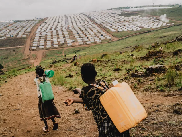 Personas refugiadas transportan suministros hacia el campamento de Busuma, donde viven comunidades congoleñas que han huido del conflicto.