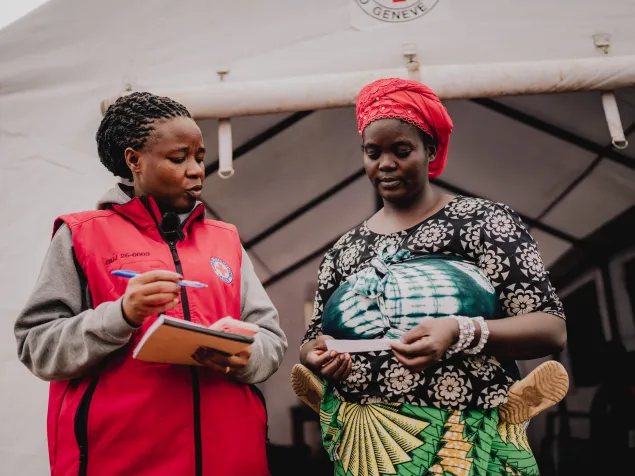 ICRC staff member Noemie Niyongere assists Congolese refugee Annuarite Yamwaka at a connectivity centre.